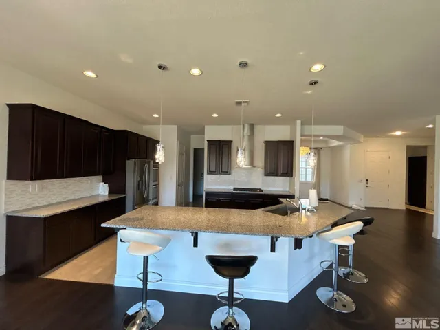 a view of kitchen with stainless steel appliances wooden floor and living room