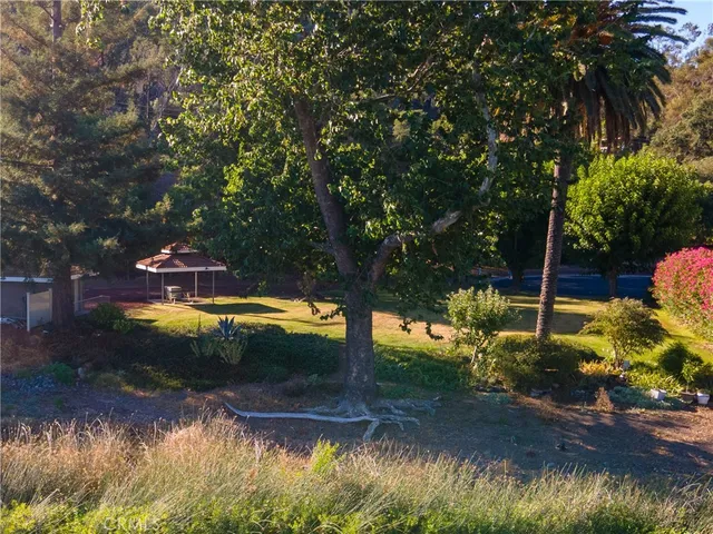 a view of a house with a big yard and large trees
