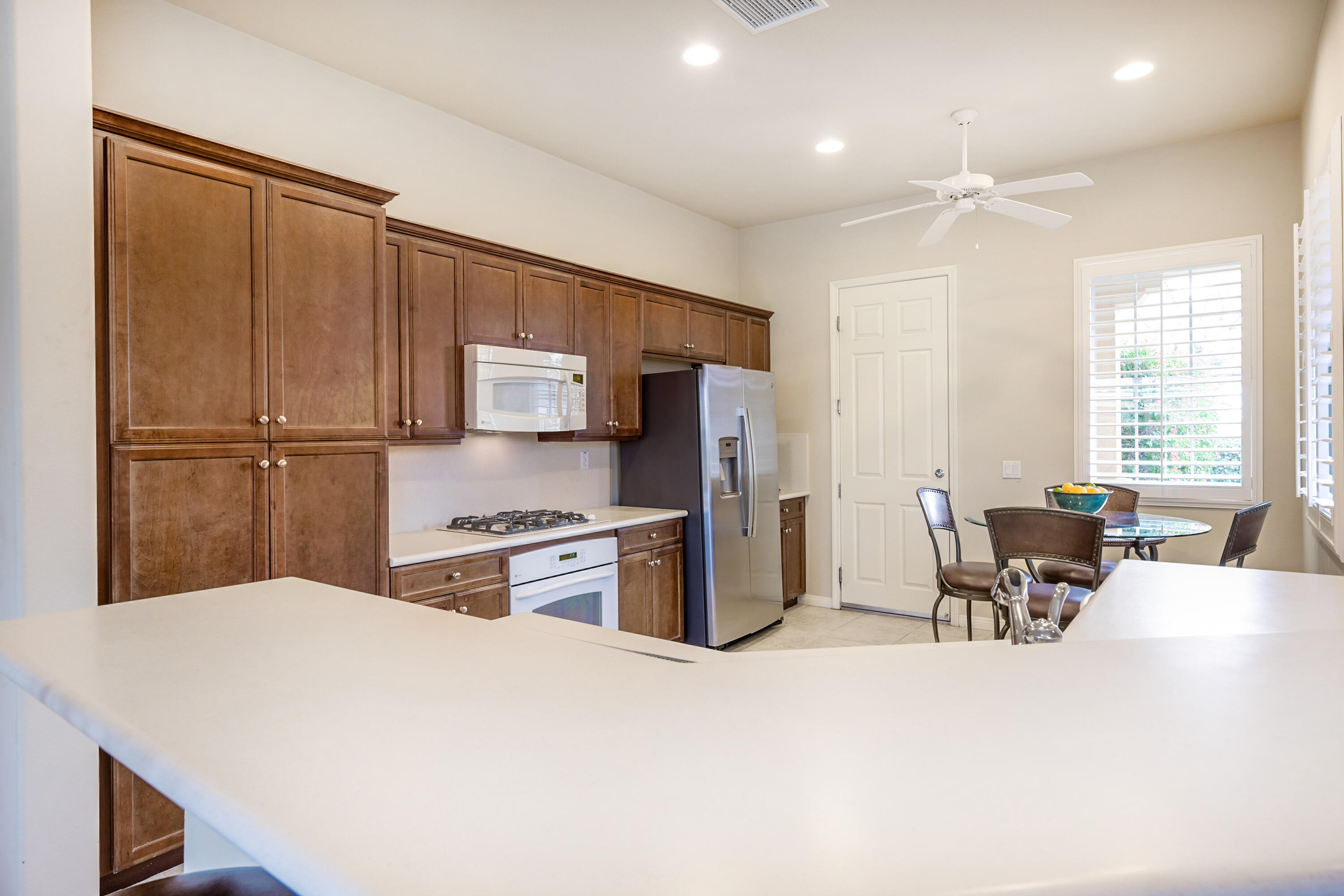 81674 Avenida Celaya Indio, CA 92203 - Photo 12 of 43 a kitchen with stainless steel appliances kitchen island granite countertop a refrigerator a stove a sink dishwasher with a dining table and chairs with wooden floor