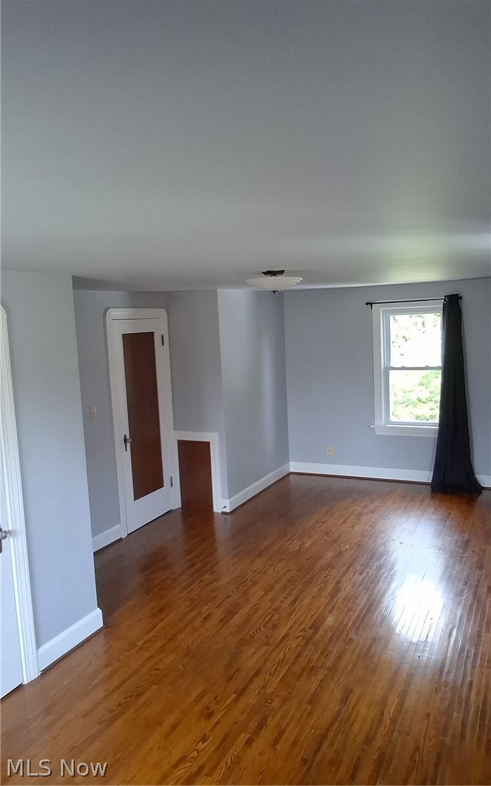 236 Bowland Road Mansfield, OH 44907 - Photo 27 of 34 Spacious room featuring hardwood flooring, light gray wall paint, white trim, a multi-pane window, and a ceiling-mounted light fixture
