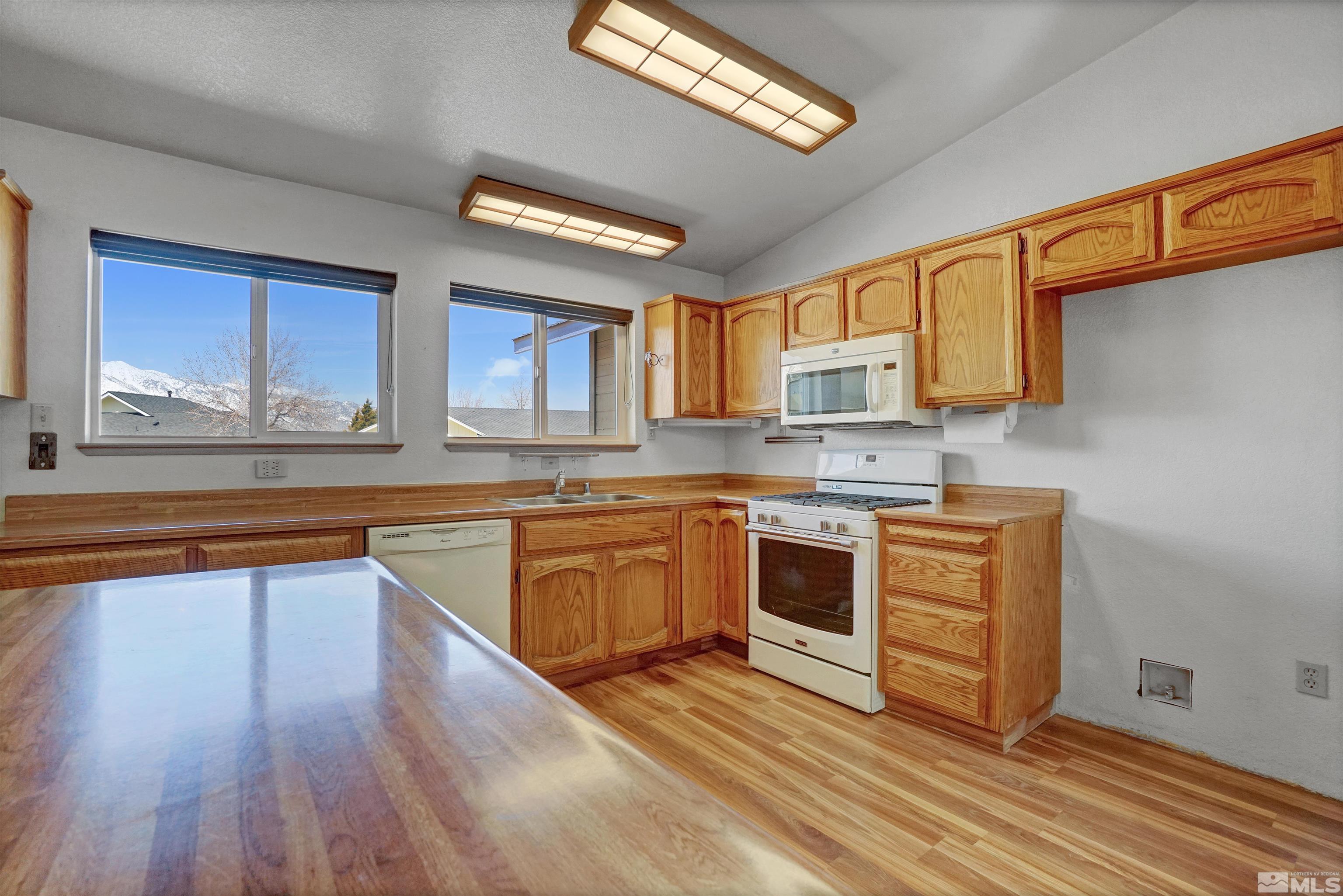 725 Addler Road Gardnerville, NV 89460 - Photo 11 of 24 a kitchen with stainless steel appliances granite countertop wooden cabinets a stove a sink and a window