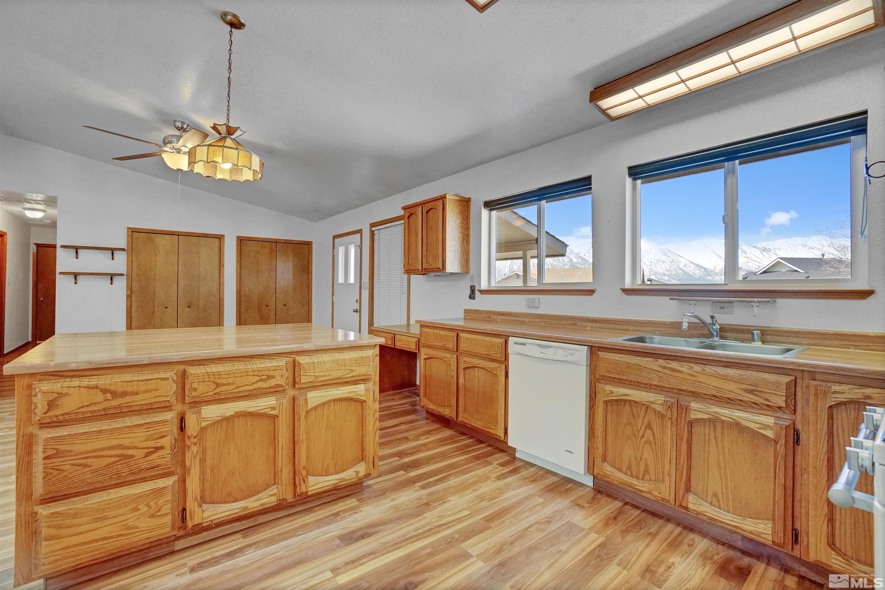 725 Addler Road Gardnerville, NV 89460 - Photo 8 of 24 a kitchen with stainless steel appliances granite countertop a stove a sink dishwasher and white cabinets with wooden floor
