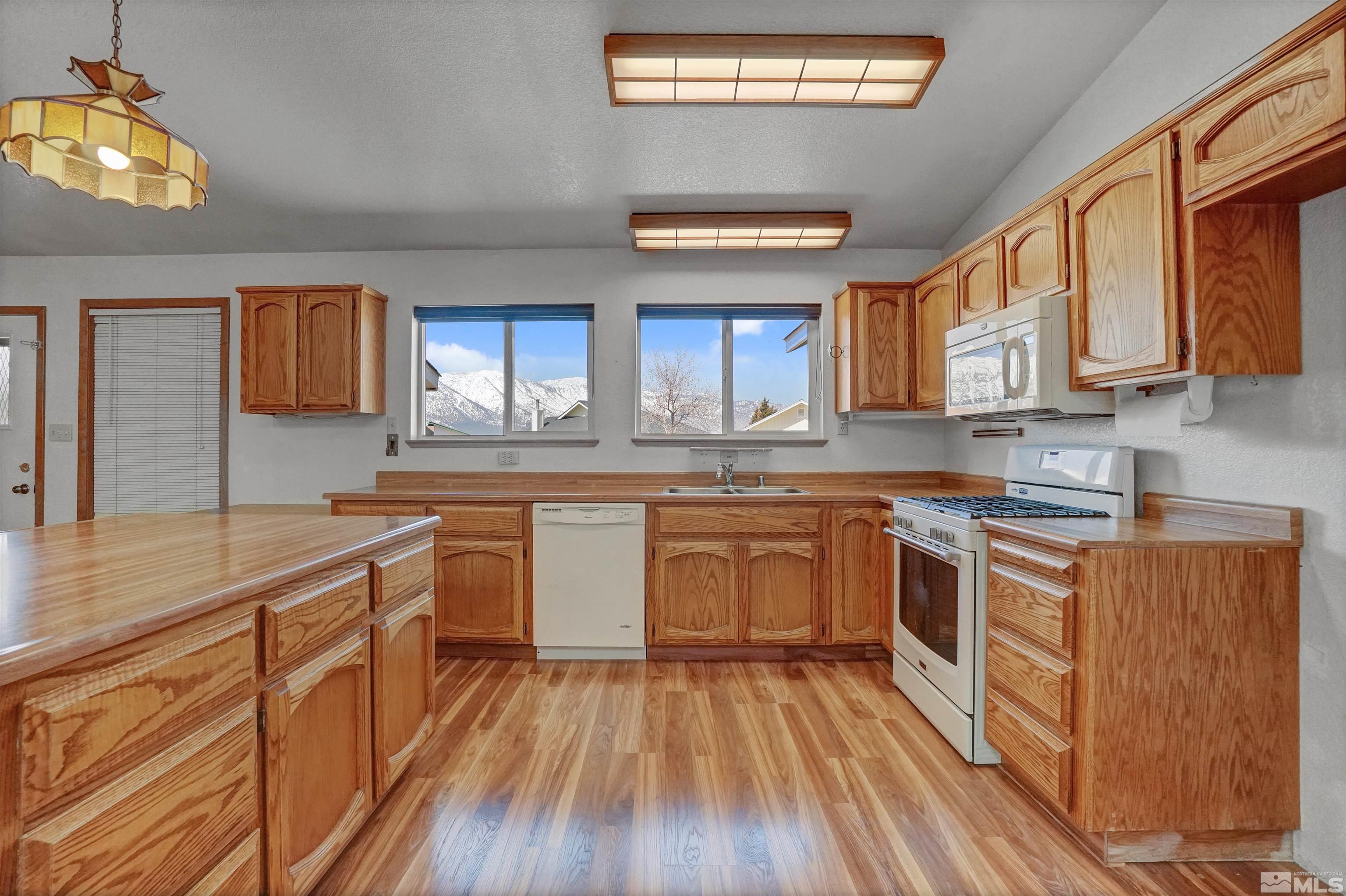 725 Addler Road Gardnerville, NV 89460 - Photo 10 of 24 a kitchen with stainless steel appliances wooden floors and wooden cabinets