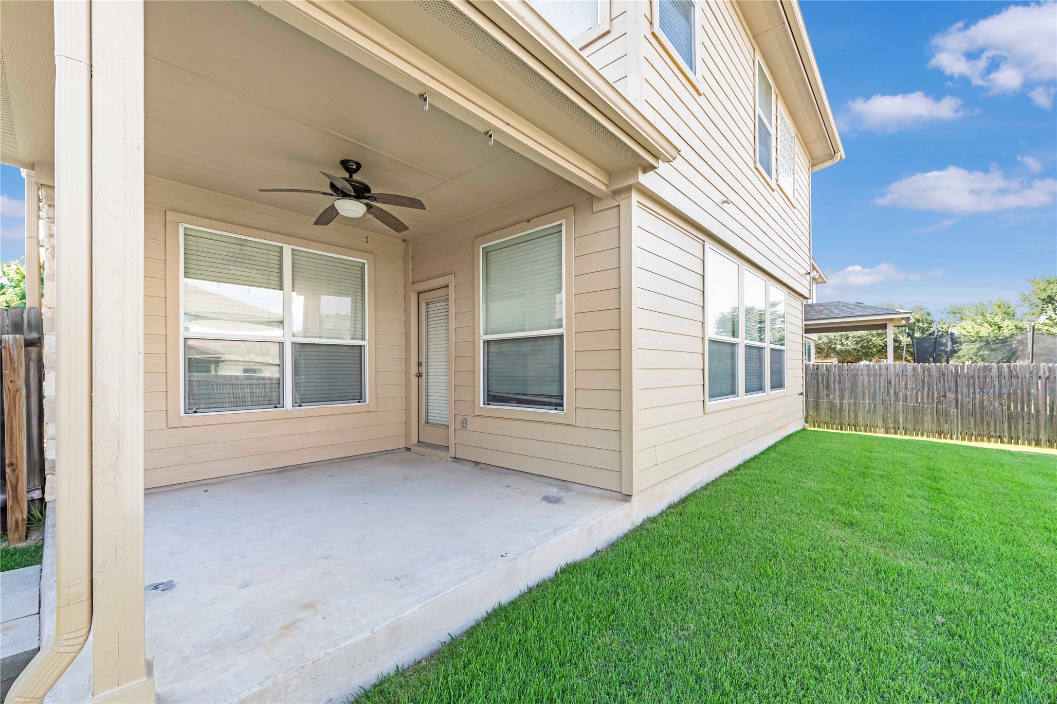 11221 Old Quarry Road Austin, TX 78717 - Photo 17 of 19 A sheltered concrete patio overlooks a grassy backyard bordered by wood fencing.