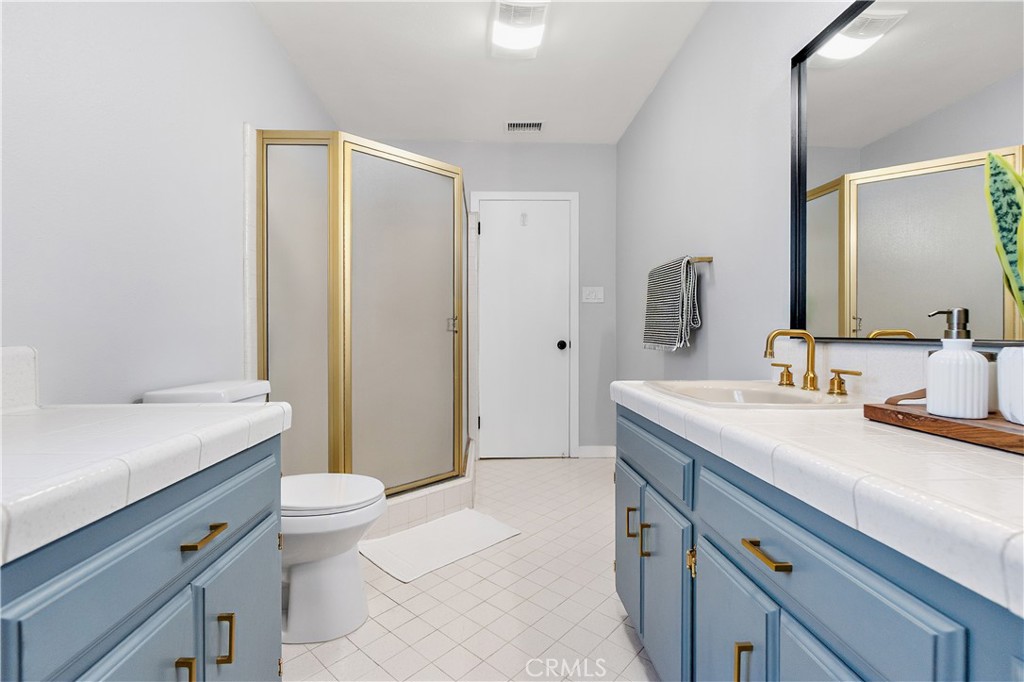 12748 Paramount Boulevard Downey, CA 90242 - Photo 29 of 72 a spacious bathroom with a granite countertop sink a toilet a mirror and shower