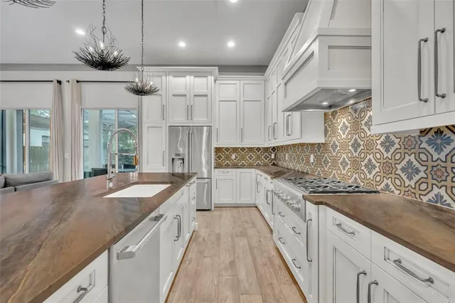 a large kitchen with granite countertop a large counter top space a sink stainless steel appliances and cabinets