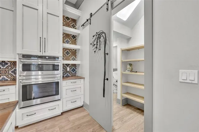 a kitchen with white cabinets and a stove with wooden floor