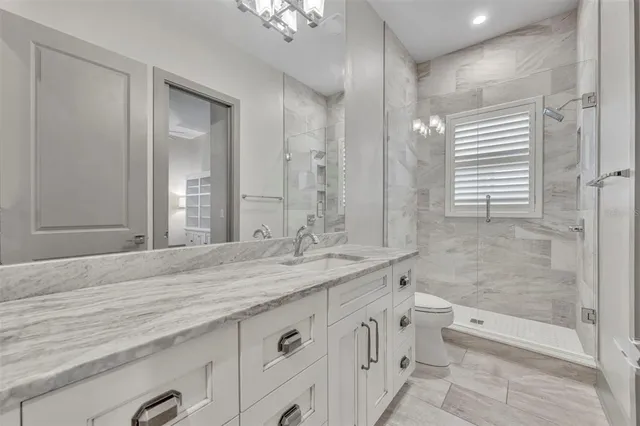 a bathroom with a granite countertop sink a toilet and shower
