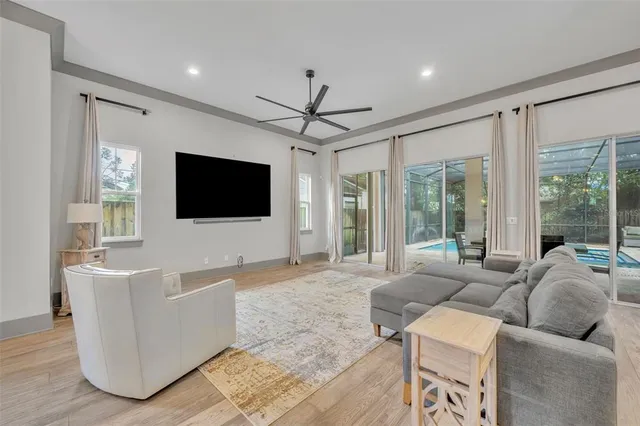 a living room with furniture a flat screen tv and a floor to ceiling window