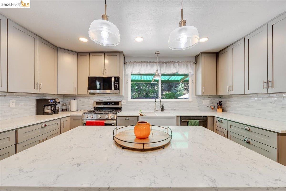 8733 Fraguero Road Sonora, CA 95370 - Photo 30 of 73 Central island with a light-toned countertop, shaker-style cabinetry, stainless steel appliances, a farmhouse sink, and recessed lighting
