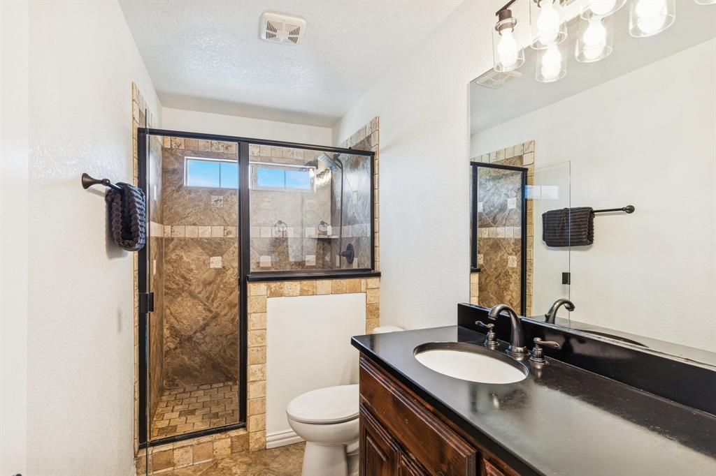 3390 Zion Hill Road Weatherford, TX 76088 - Photo 23 of 40 a bathroom with a granite countertop sink a toilet a mirror and shower