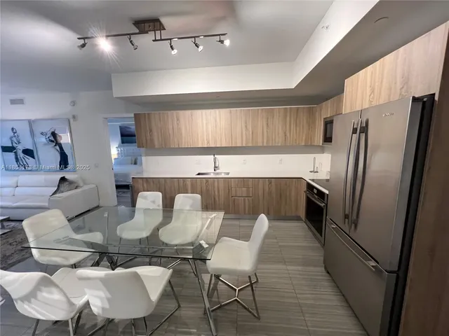 a kitchen with stainless steel appliances a dining table chairs and a refrigerator