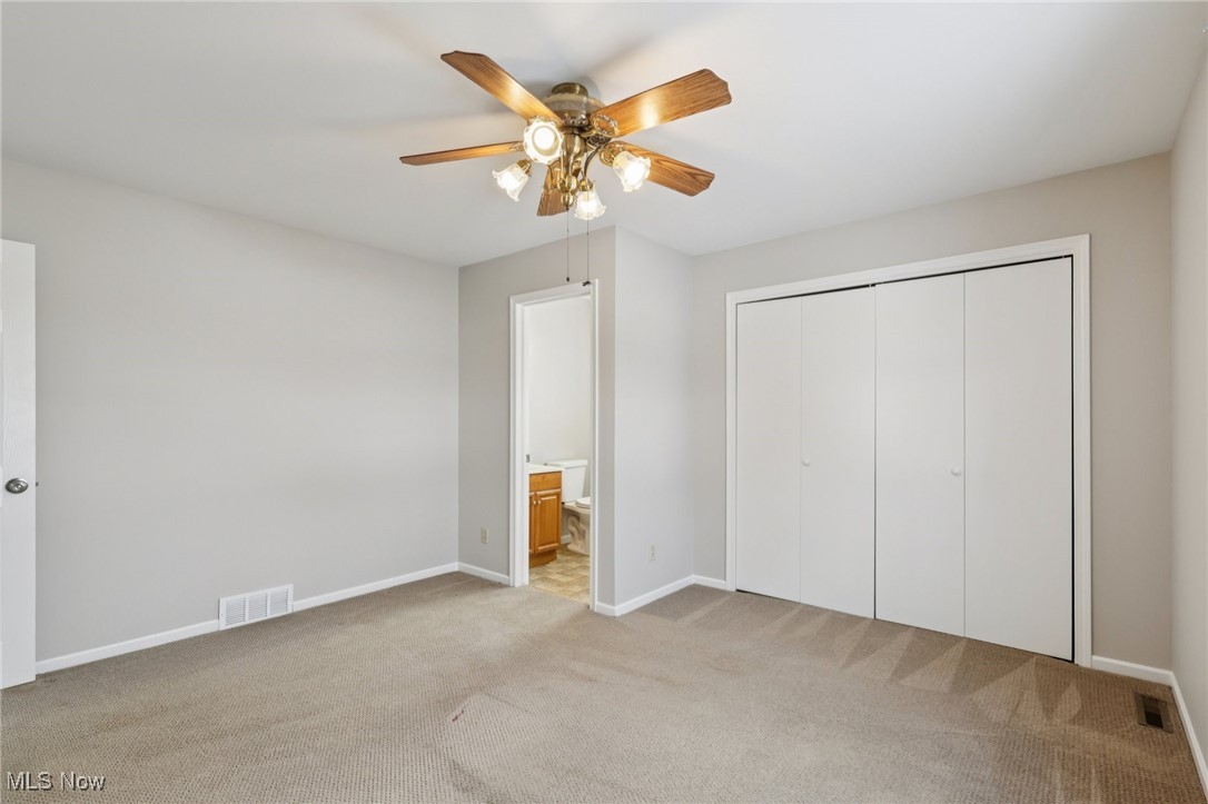 611 Wilson Street Struthers, OH 44471 - Photo 18 of 44 Unfurnished bedroom featuring light colored carpet, connected bathroom, ceiling fan, and a closet