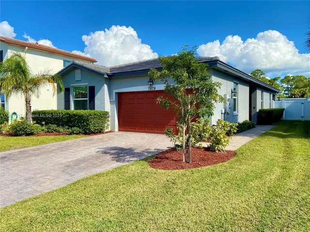 a front view of a house with a yard and potted plants