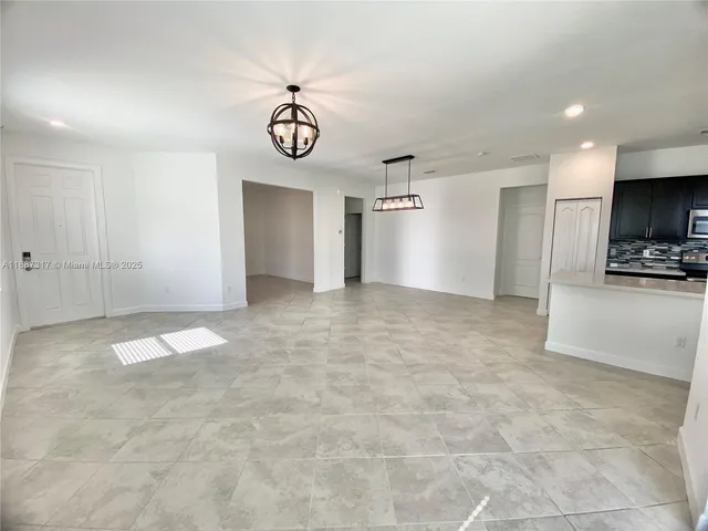 a view of a livingroom with kitchen and chandelier