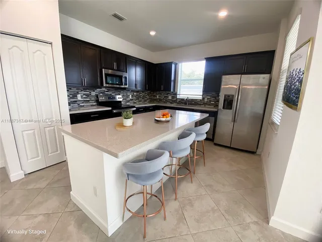 a kitchen with stainless steel appliances a refrigerator a stove a sink a microwave a counter space and cabinets