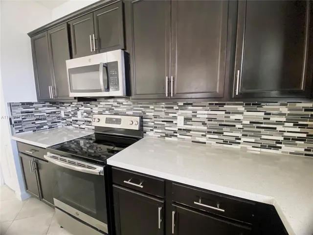 a kitchen with granite countertop a sink stove and cabinets