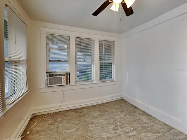 an empty room with ceiling fan and window