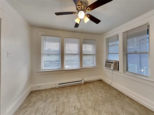 an empty room with chandelier fan and windows