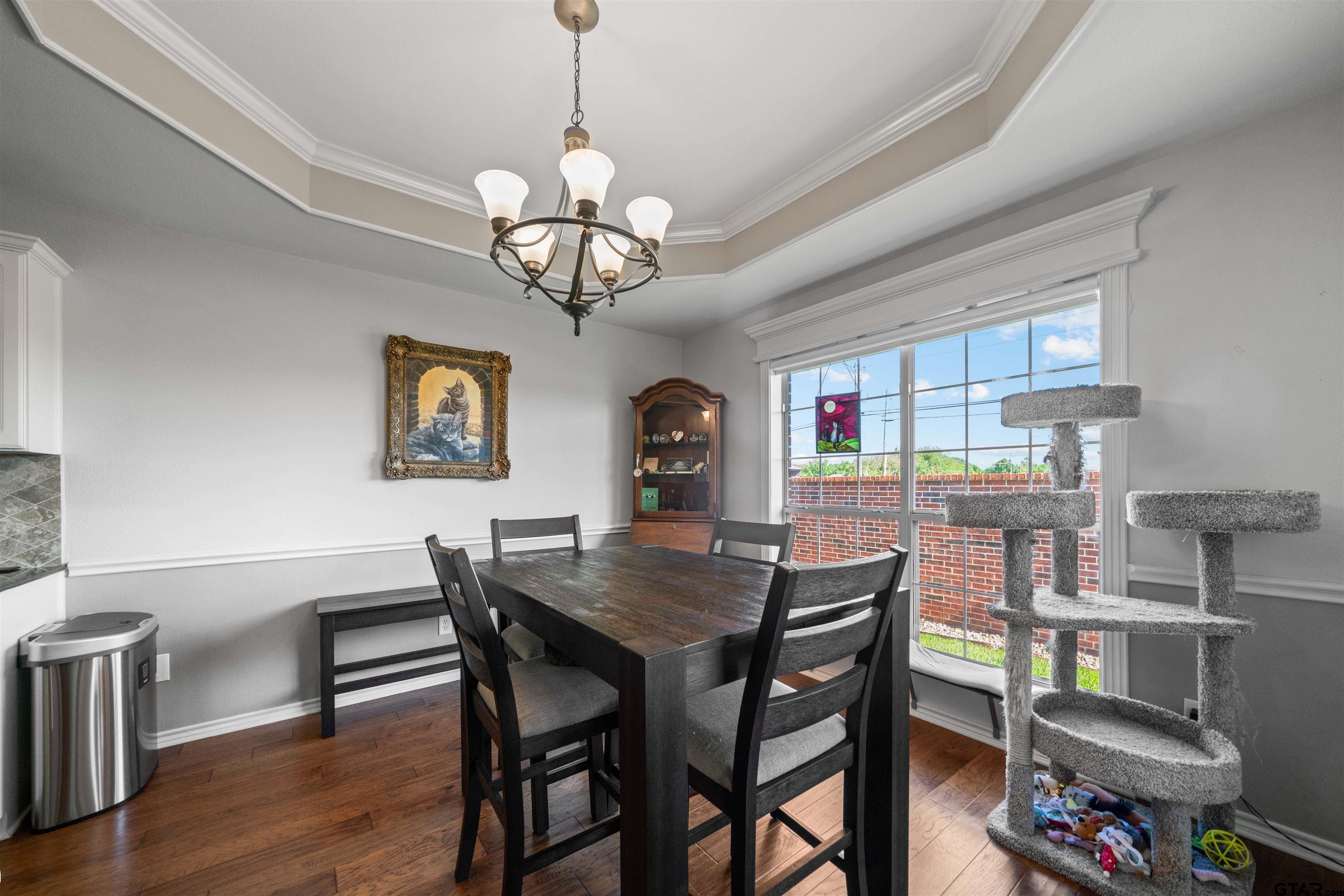 1521 Rice Road, Unit A105 Tyler, TX 75703 - Photo 12 of 28 a view of a dining room with furniture wooden floor and chandelier