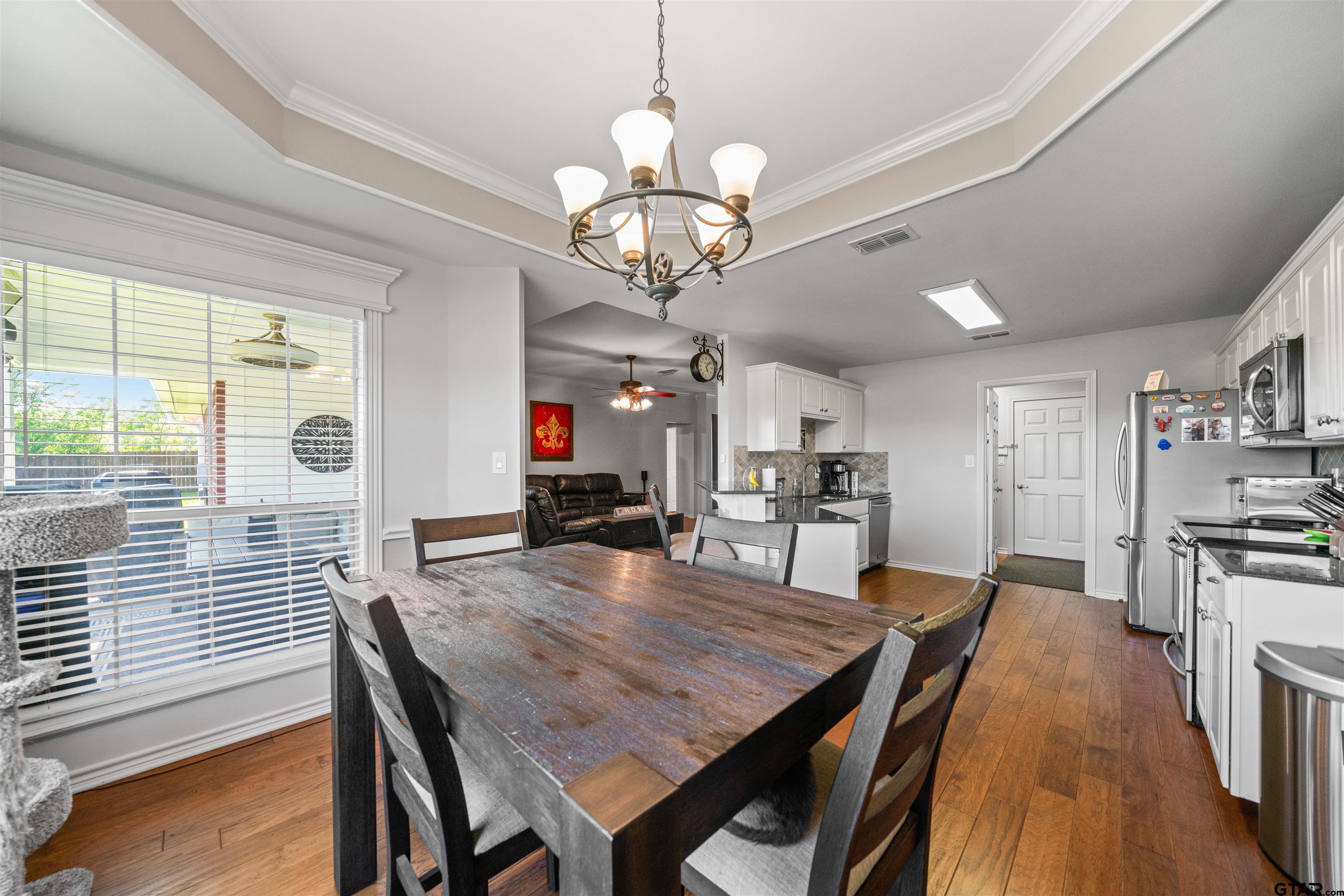 1521 Rice Road, Unit A105 Tyler, TX 75703 - Photo 15 of 28 a view of a dining room with furniture a chandelier and wooden floor