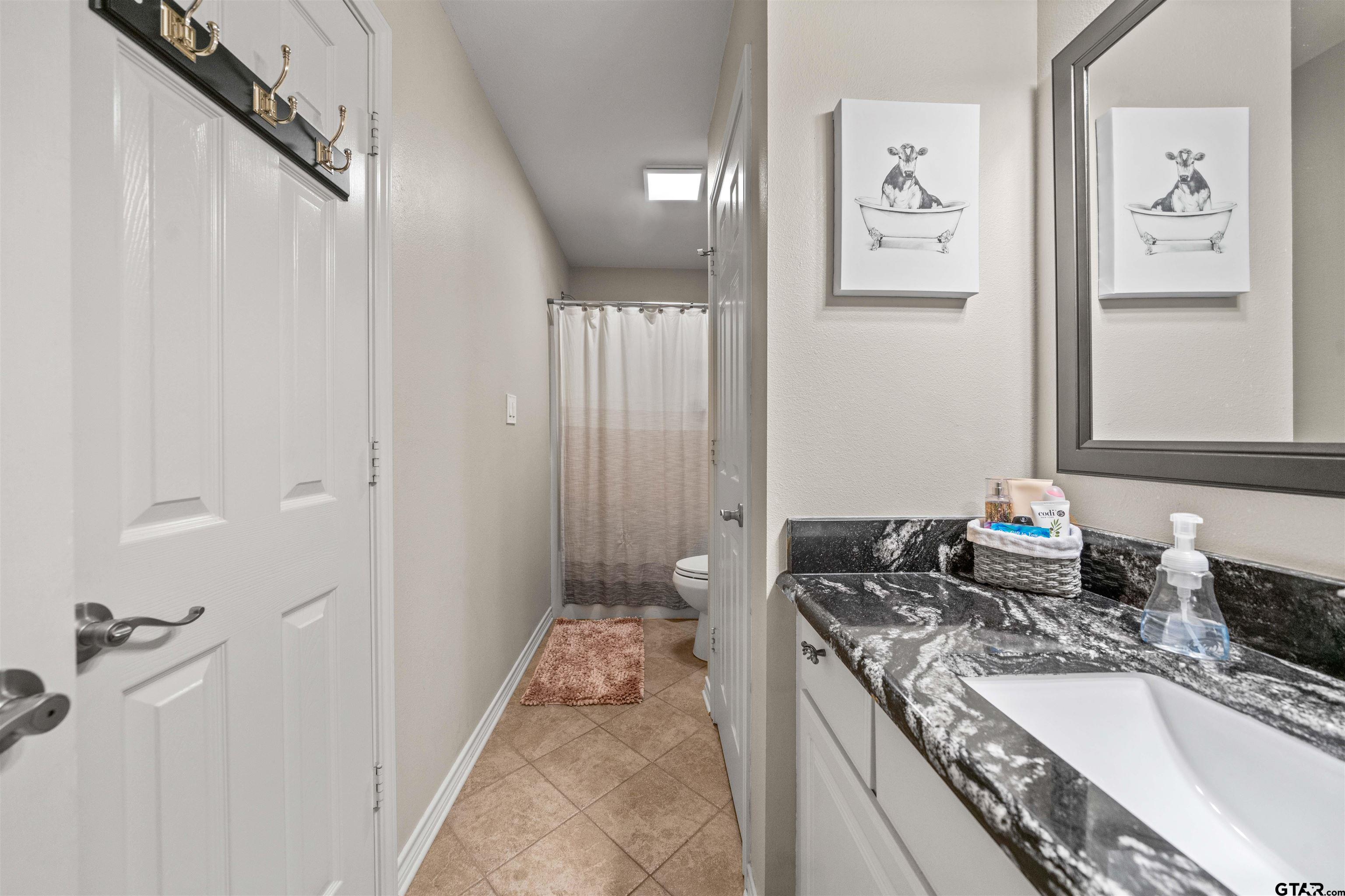 1521 Rice Road, Unit A105 Tyler, TX 75703 - Photo 17 of 28 a bathroom with a granite countertop sink a toilet and a bathtub