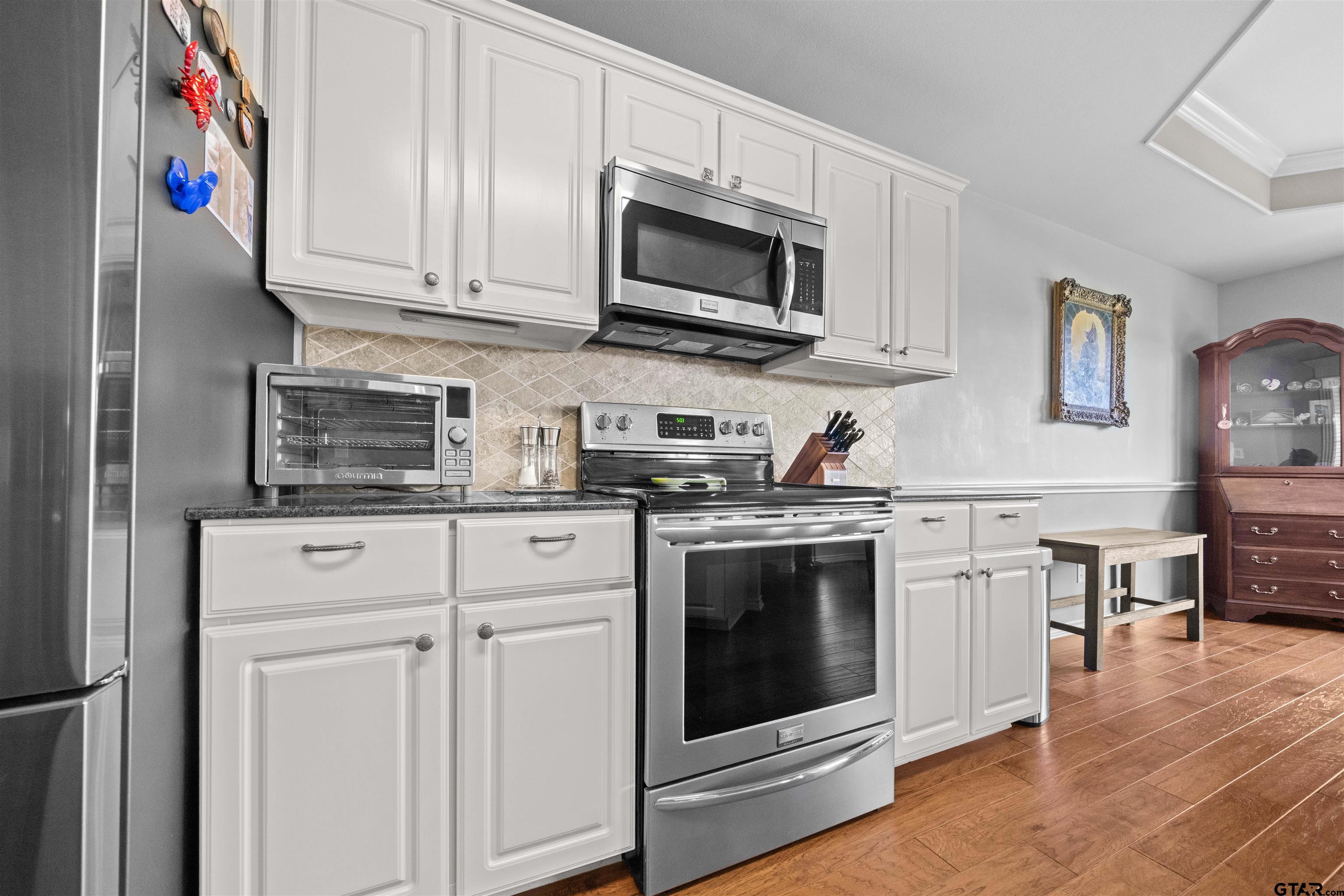 1521 Rice Road, Unit A105 Tyler, TX 75703 - Photo 9 of 28 a kitchen with stainless steel appliances granite countertop a stove a microwave and cabinets