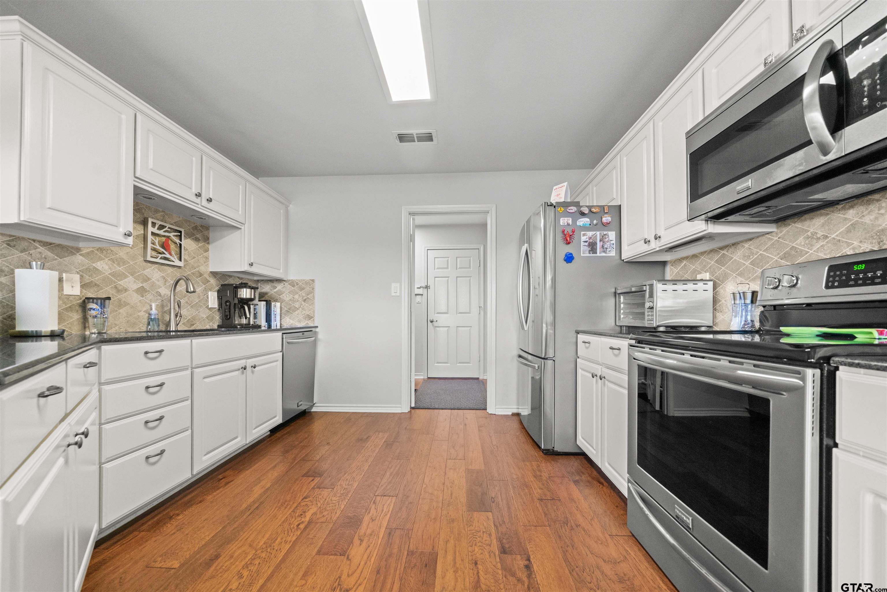 1521 Rice Road, Unit A105 Tyler, TX 75703 - Photo 10 of 28 a kitchen with stainless steel appliances granite countertop a stove a sink and a refrigerator