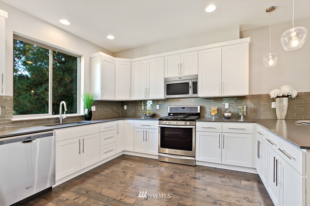315 South 47th Street Renton, WA 98055 - Photo 4 of 22 a large white kitchen with stainless steel appliances granite countertop a stove a sink dishwasher and a microwave oven with cabinets