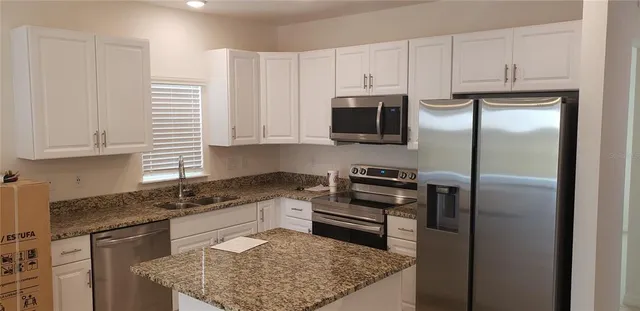 a kitchen with stainless steel appliances granite countertop a refrigerator sink and stove