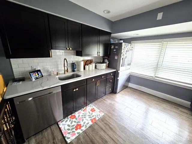 a kitchen with stainless steel appliances kitchen island granite countertop a sink dishwasher stove top oven and cabinets with wooden floor