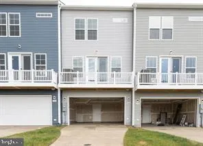 a front view of a building with a garden and parking