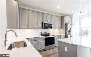 a kitchen with granite countertop a sink a counter top space stainless steel appliances and cabinets