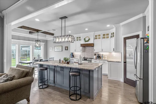 a kitchen with kitchen island granite countertop stove top oven a sink a dining table and chairs