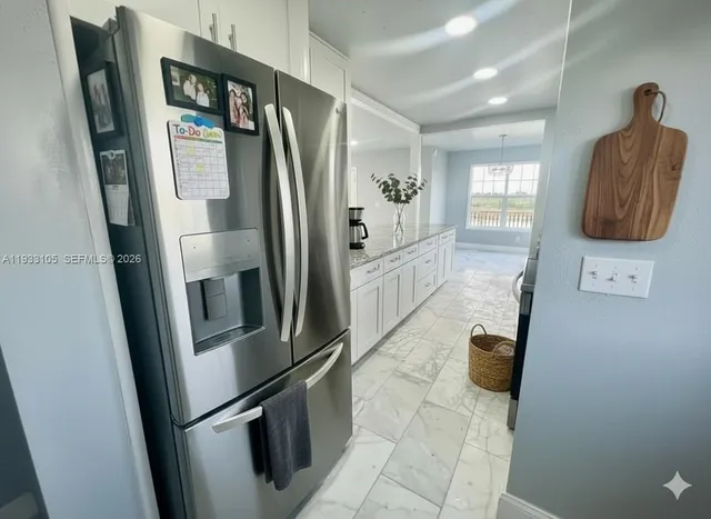 a view of a refrigerator in kitchen and an empty room