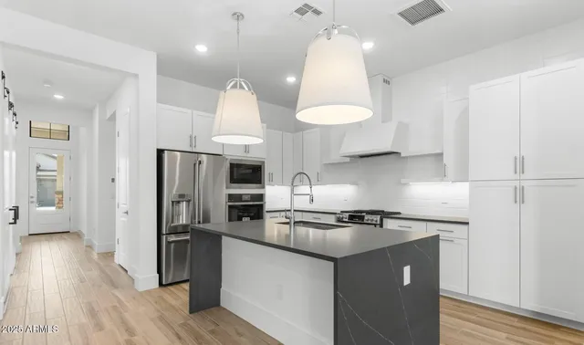 a kitchen with stainless steel appliances granite countertop a refrigerator a sink and a stove