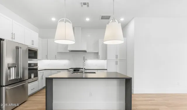 a kitchen with stainless steel appliances a sink a stove a refrigerator and island