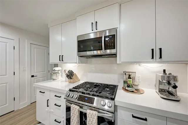 a kitchen with stainless steel appliances a white stove top oven and cabinets