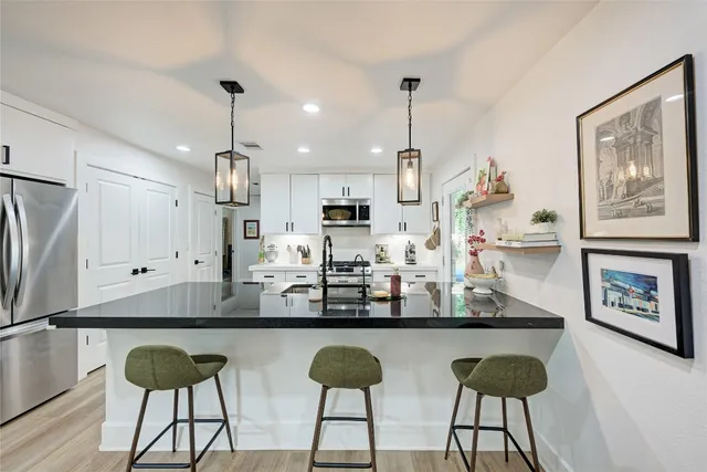 a kitchen with stainless steel appliances granite countertop a refrigerator a sink and a stove