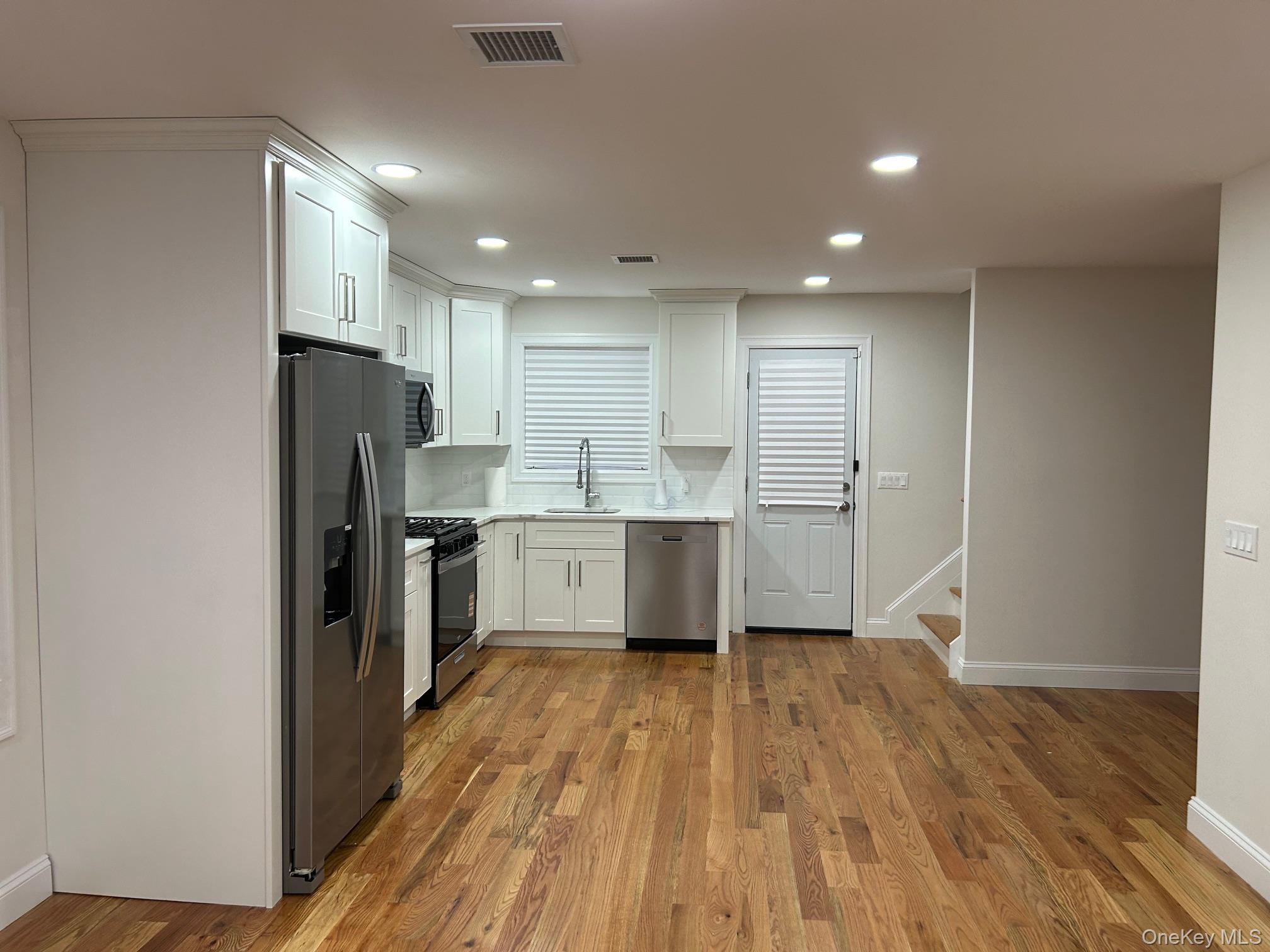 53 Hewlett Street Hempstead, NY 11550 - Photo 2 of 3 Kitchen with white cabinets, stainless steel appliances, dark wood-style flooring, backsplash, and recessed lighting
