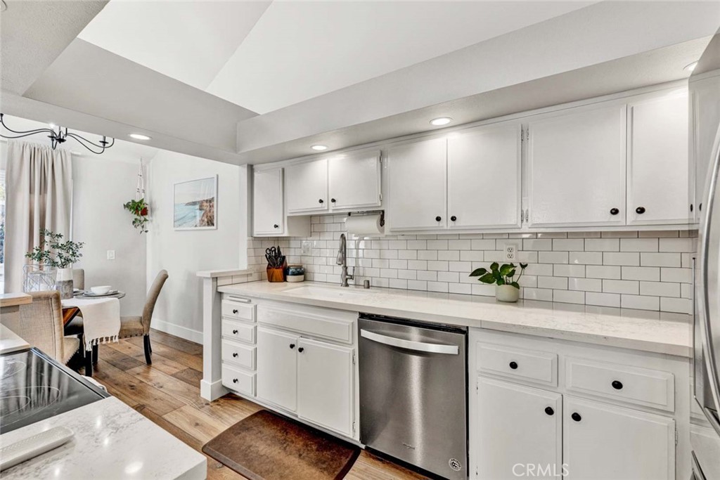 789 Grayling Bay Costa Mesa, CA 92626 - Photo 13 of 42 a kitchen with granite countertop white cabinets white appliances a sink and chairs