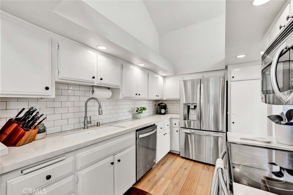 789 Grayling Bay Costa Mesa, CA 92626 - Photo 10 of 42 a kitchen with stainless steel appliances a sink cabinets and wooden floor