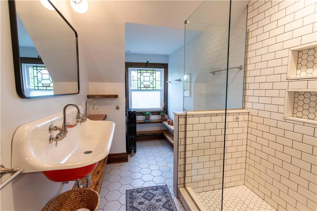 5901 Hampton Street Pittsburgh, PA 15206 - Photo 32 of 42 a bathroom with a sink a mirror and a shower