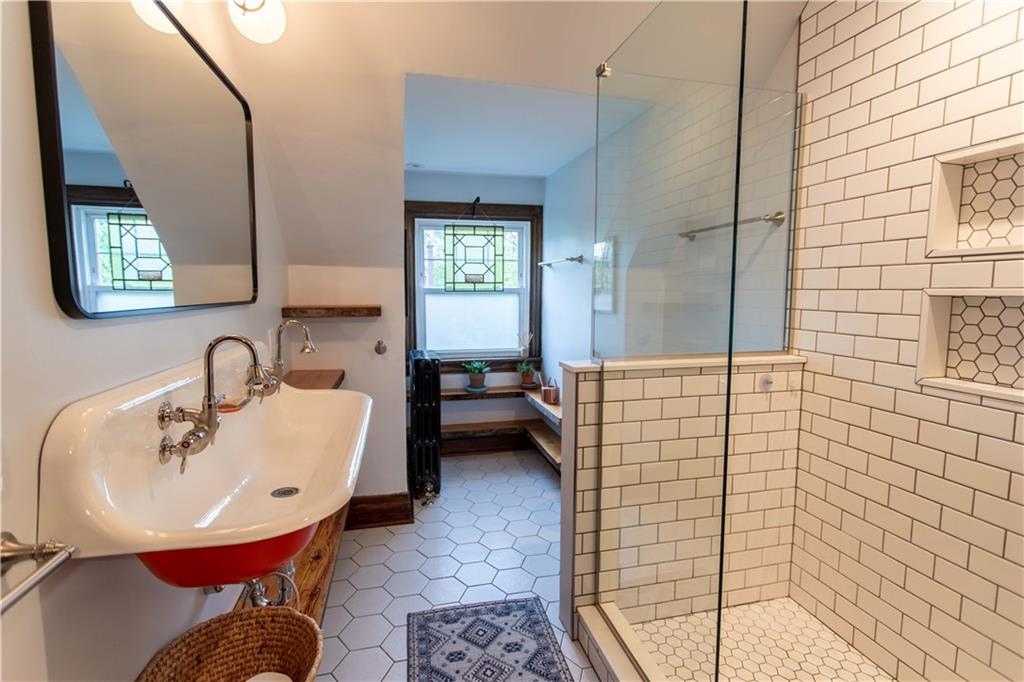 5901 Hampton Street Pittsburgh, PA 15206 - Photo 33 of 42 a bathroom with a sink a mirror and a shower