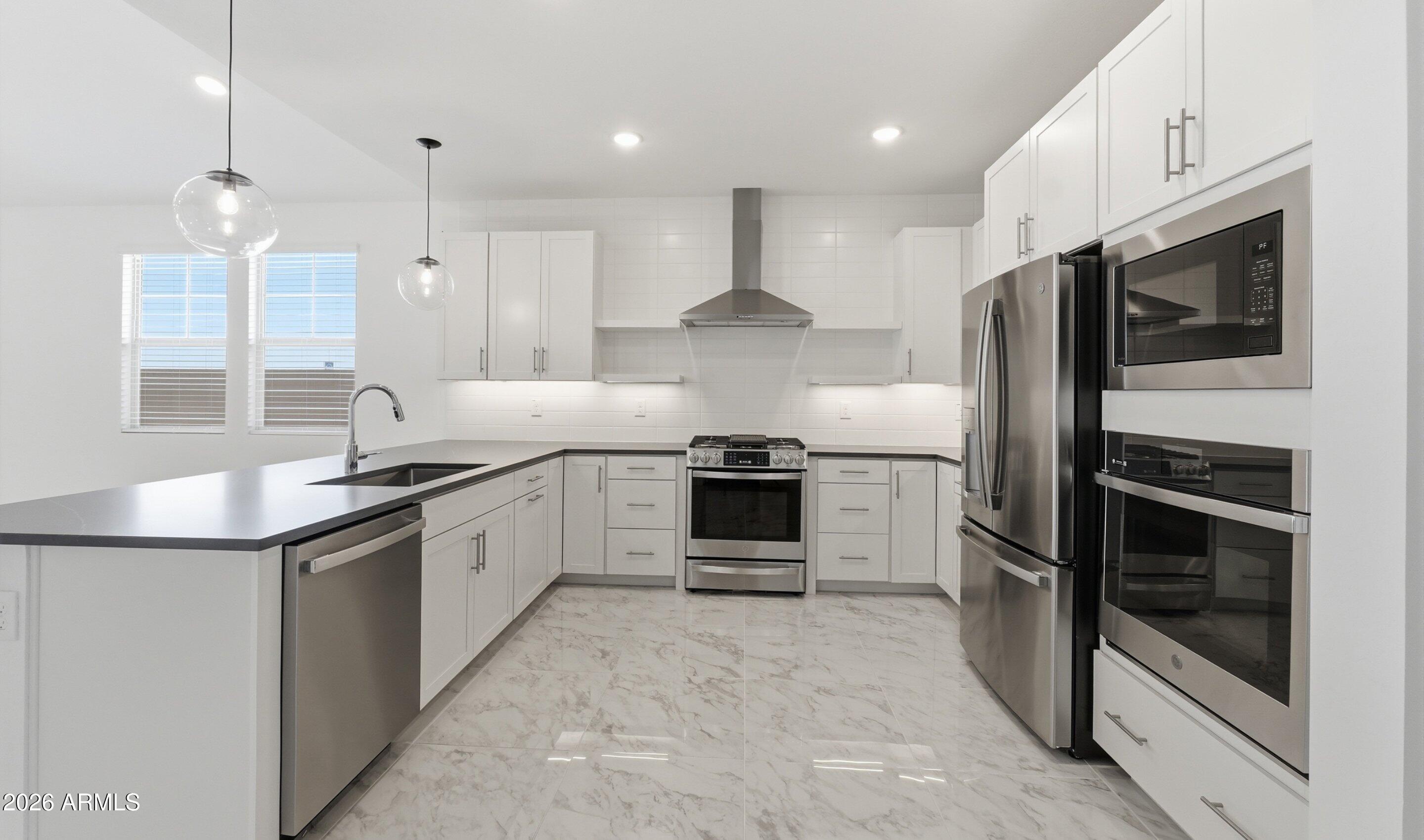 7779 West Sands Road Glendale, AZ 85303 - Photo 2 of 37 a large kitchen with stainless steel appliances kitchen island granite countertop a stove a sink and a refrigerator