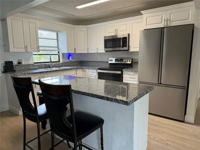 a kitchen with stainless steel appliances a refrigerator a stove a sink and white cabinets