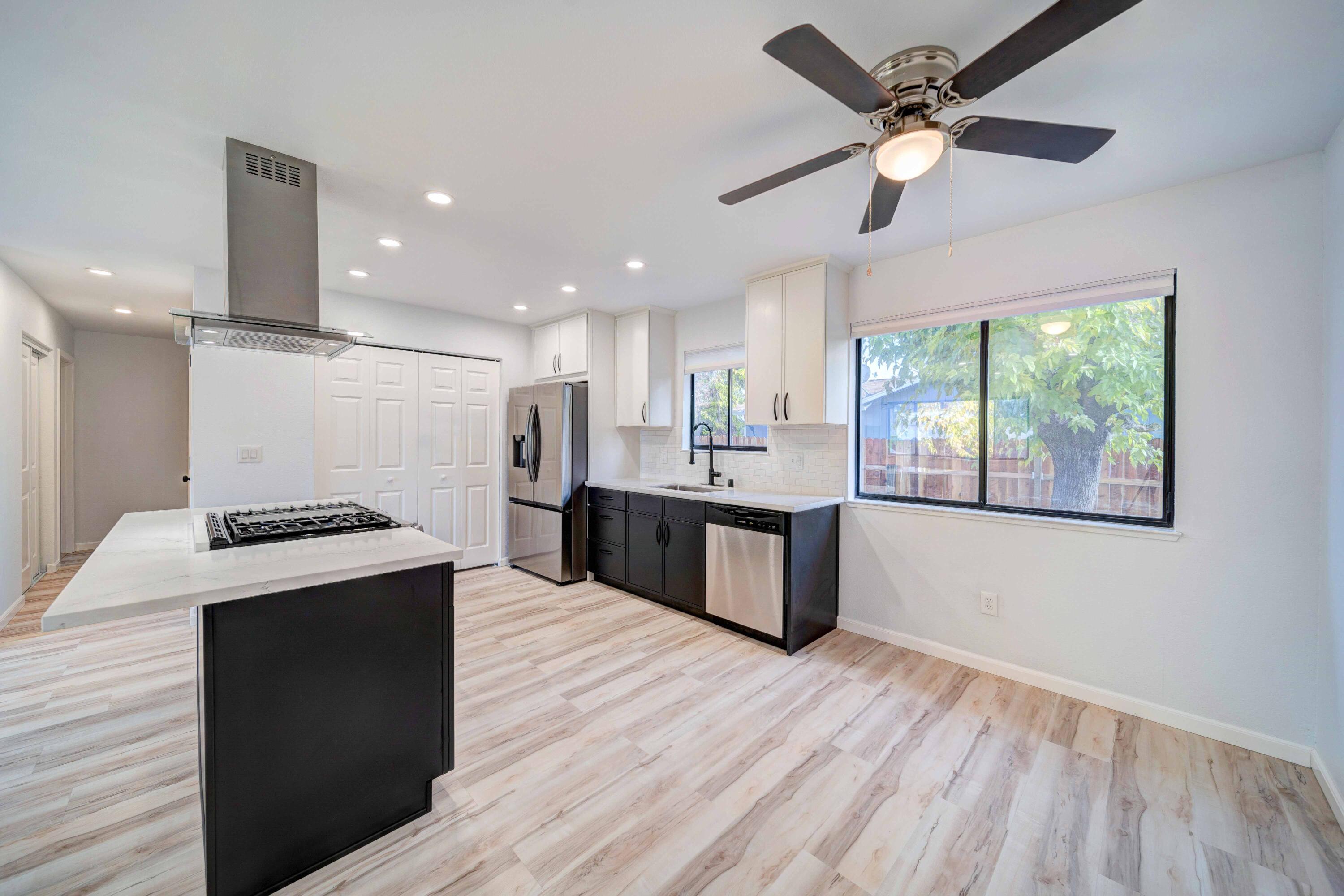 1611 2nd Street Anderson, CA 96007 - Photo 7 of 20 a large kitchen with stainless steel appliances granite countertop a stove a sink dishwasher and a refrigerator with wooden floor