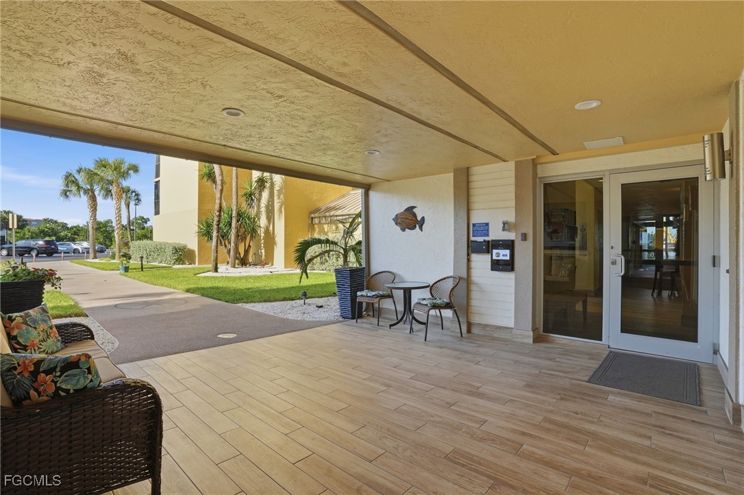 400 Lenell Road, Unit 706 Fort Myers Beach, FL 33931 - Photo 4 of 33 a view of a patio with table and chairs potted plants with wooden floor
