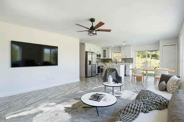 a living room with furniture a flat screen tv and kitchen view