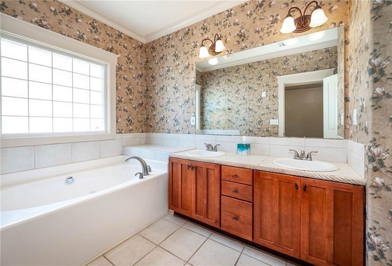 65 Orchard Drive Covington, GA 30014 - Photo 19 of 50 a bathroom with a bathtub a double vanity sink and mirror